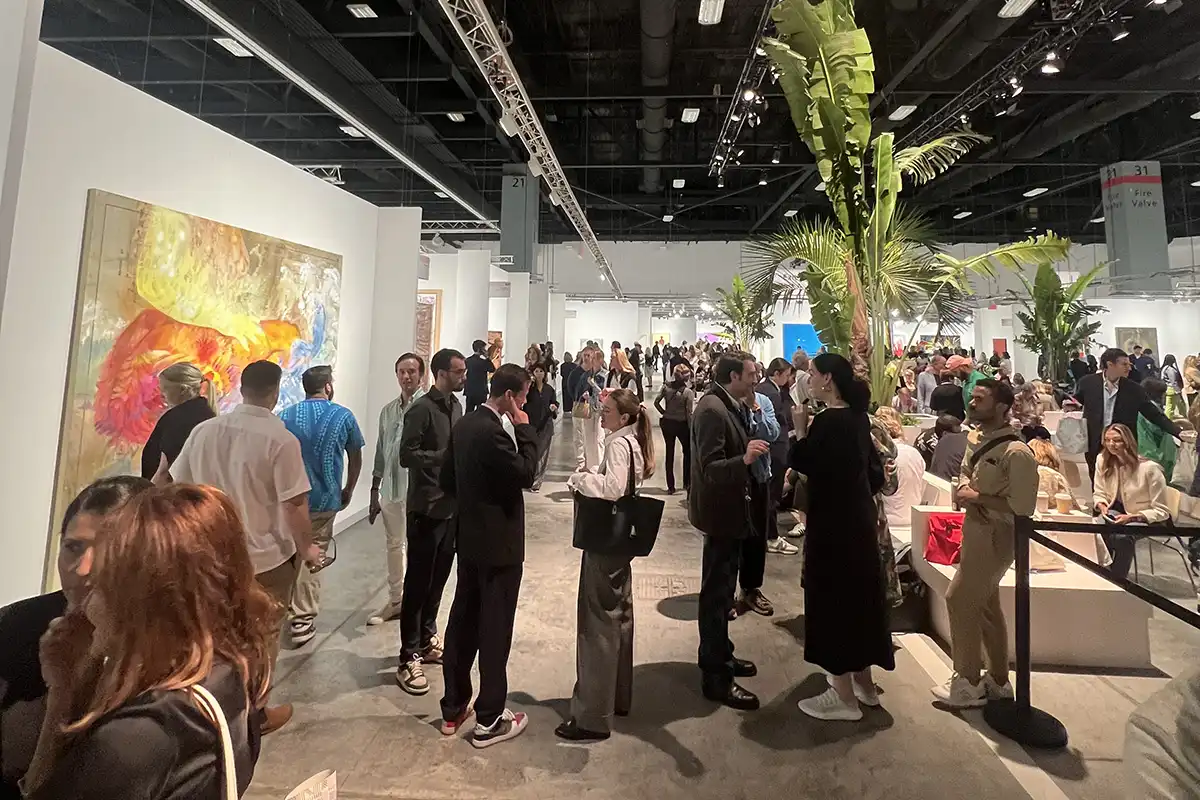 Interior de una galería con visitantes observando obras